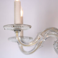 American 20th century, clear-cut crystal and brass chandelier, with five arms and a central stem with a raised dot, studded central sphere, cross-hatched bottom, and matching ribbed, lobed ball finial; the arms extend from the bottom with elegant curvature, terminating with fluted bobeche displaying shallow grooves and channels; 1930’s. diameter: 20 in. (51 cm), drop: 23 in. (58 cm)